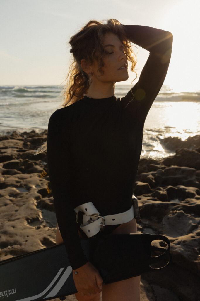 Woman in free-diving gear, wearing a wetsuit, mask,  weight belt and snorkel, preparing to dive into clear blue waters