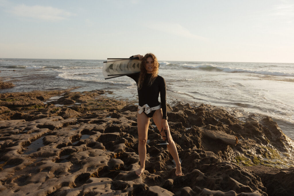 Woman in free-diving gear, wearing a wetsuit, mask, weight belt and snorkel, preparing to dive into clear blue waters